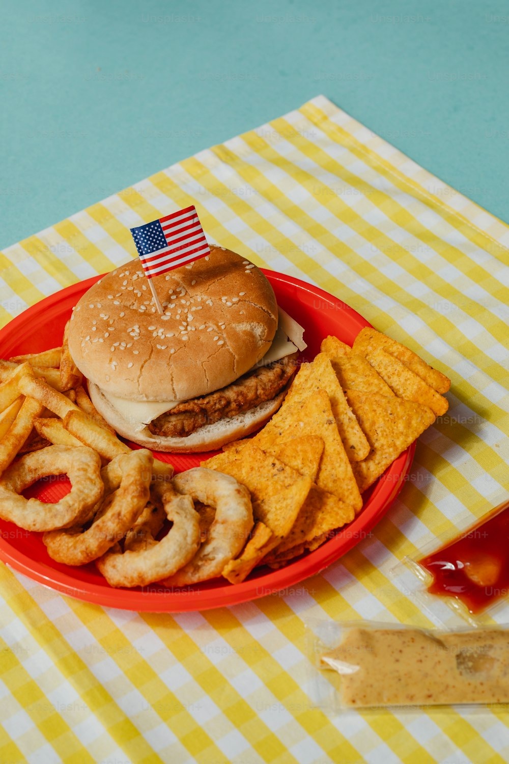 a plate with a hamburger, onion rings, and french fries