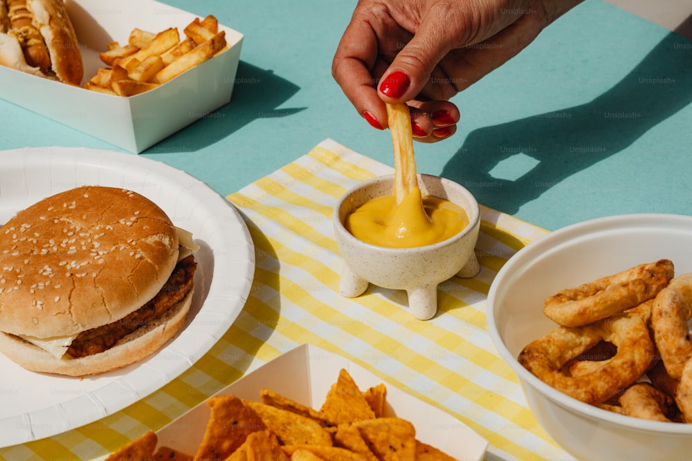 a person is dipping sauce into a hamburger