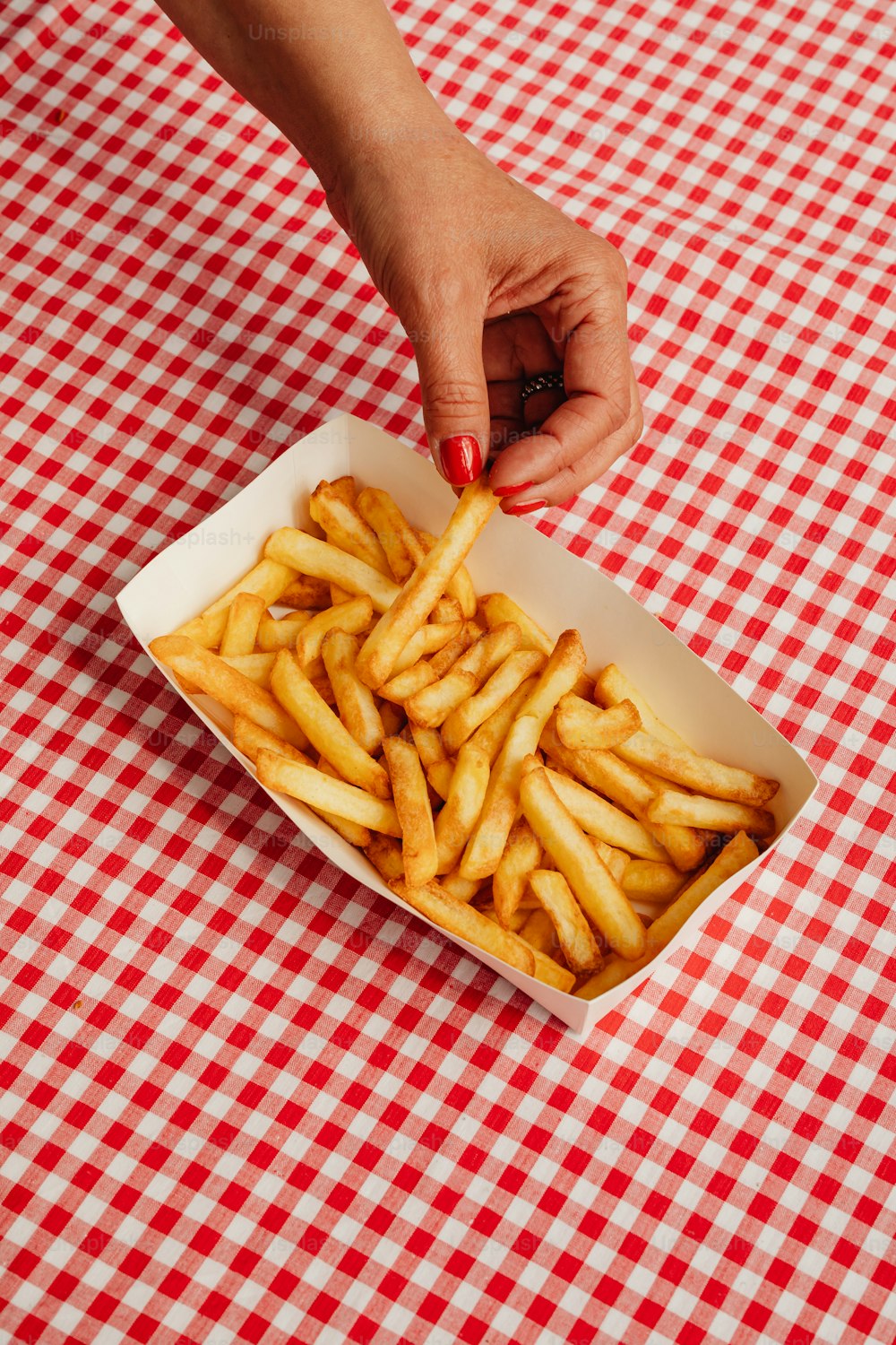 a person reaching for french fries in a box