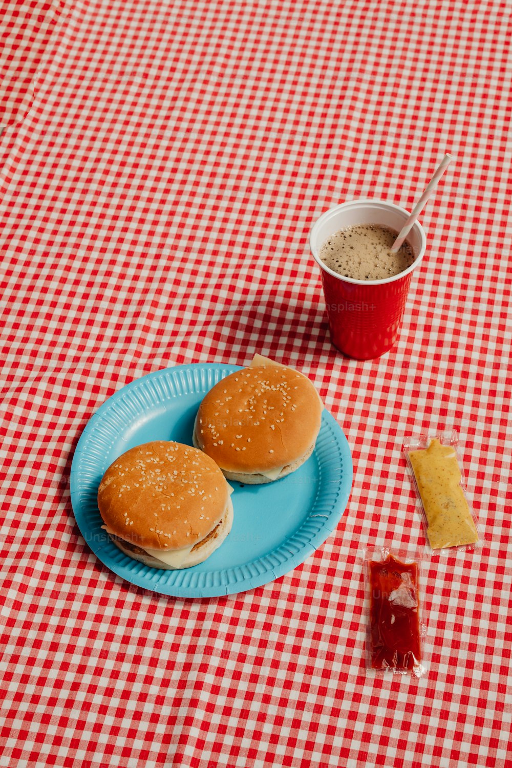 two hamburgers on a blue plate next to a cup of coffee