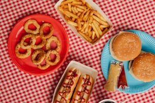 a table topped with plates of food next to a red and white checkered table