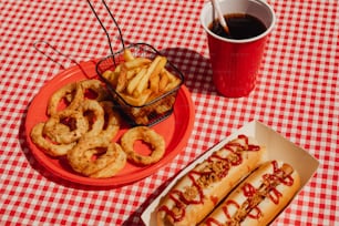 Dos perritos calientes y aros de cebolla en un mantel a cuadros rojos y blancos