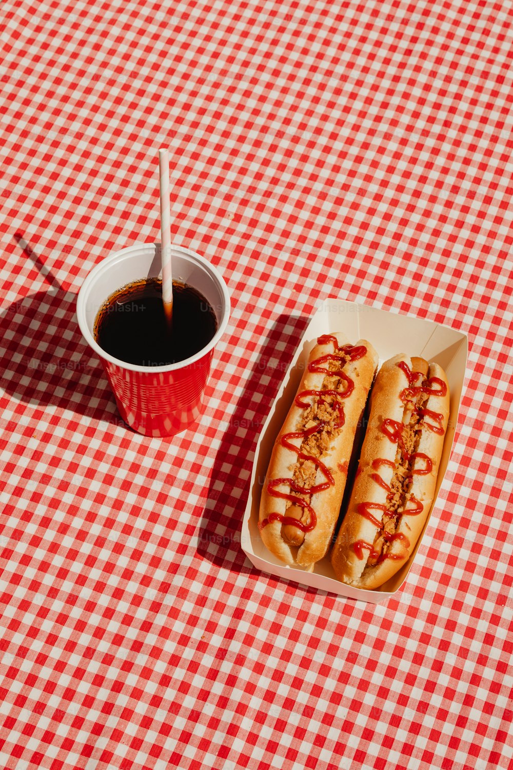a couple of hot dogs sitting on top of a red and white checkered table