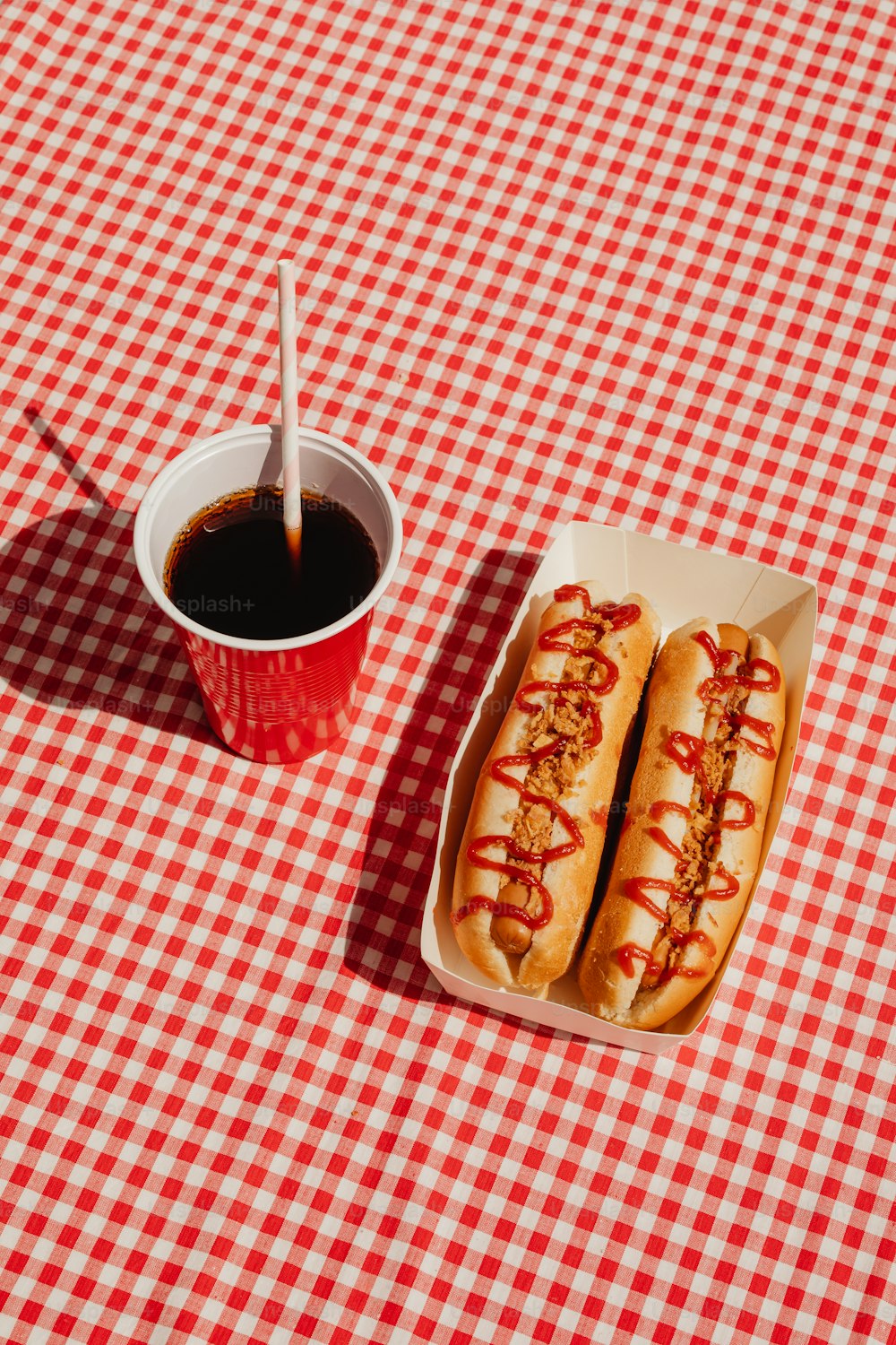 a couple of hot dogs sitting on top of a red and white checkered table