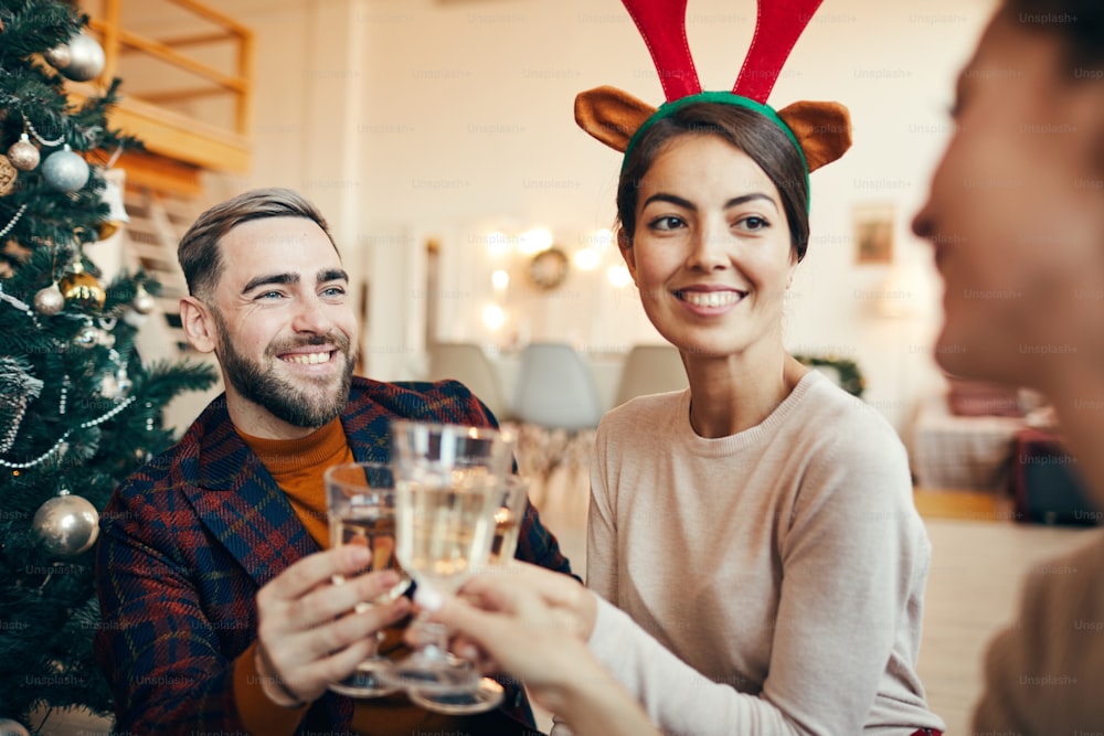 Portrait d’un homme adulte élégant souriant joyeusement tout en faisant claquer des coupes de champagne avec des amis pendant la fête de Noël