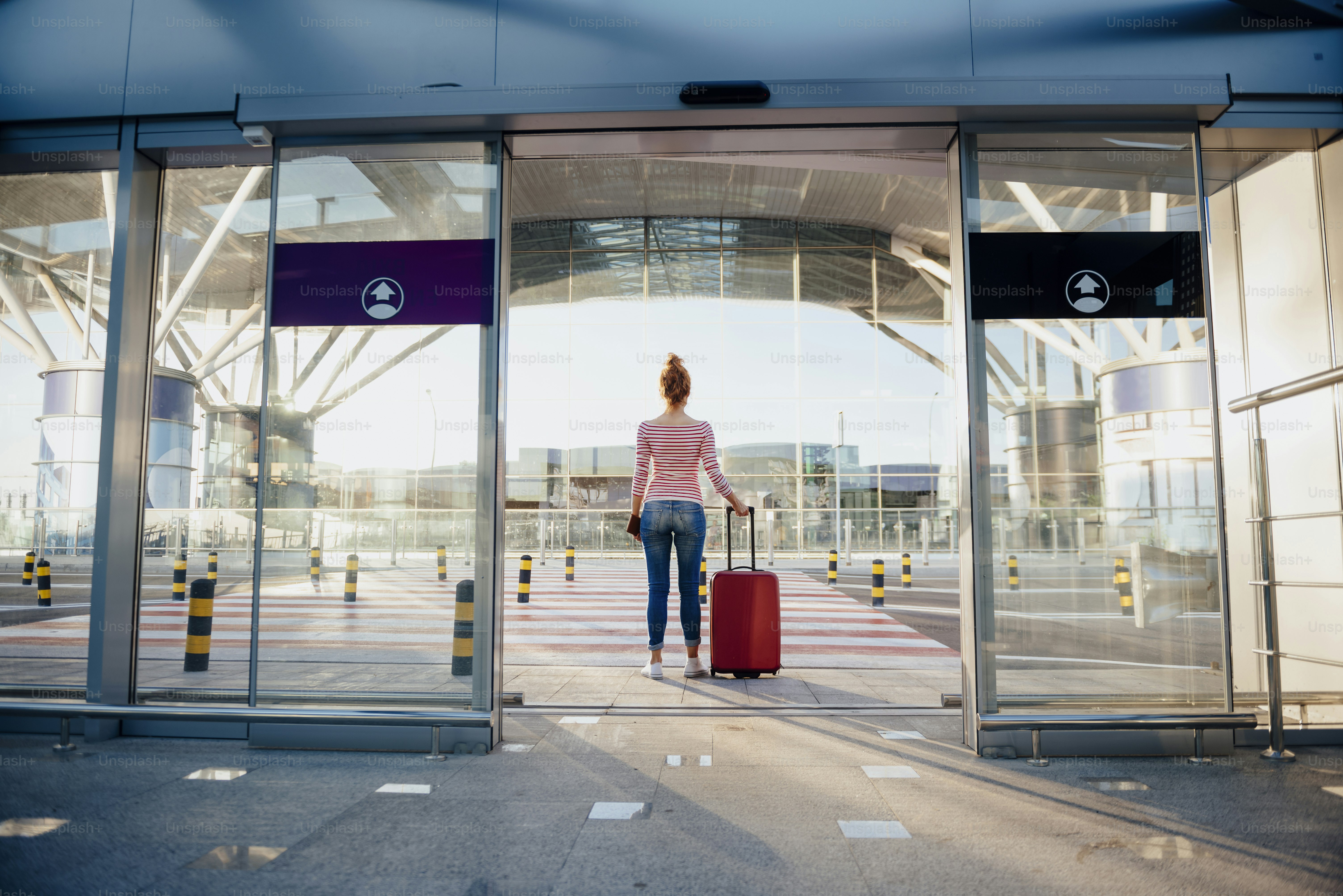 Woman is crossing road to airport with luggage and plane tickets