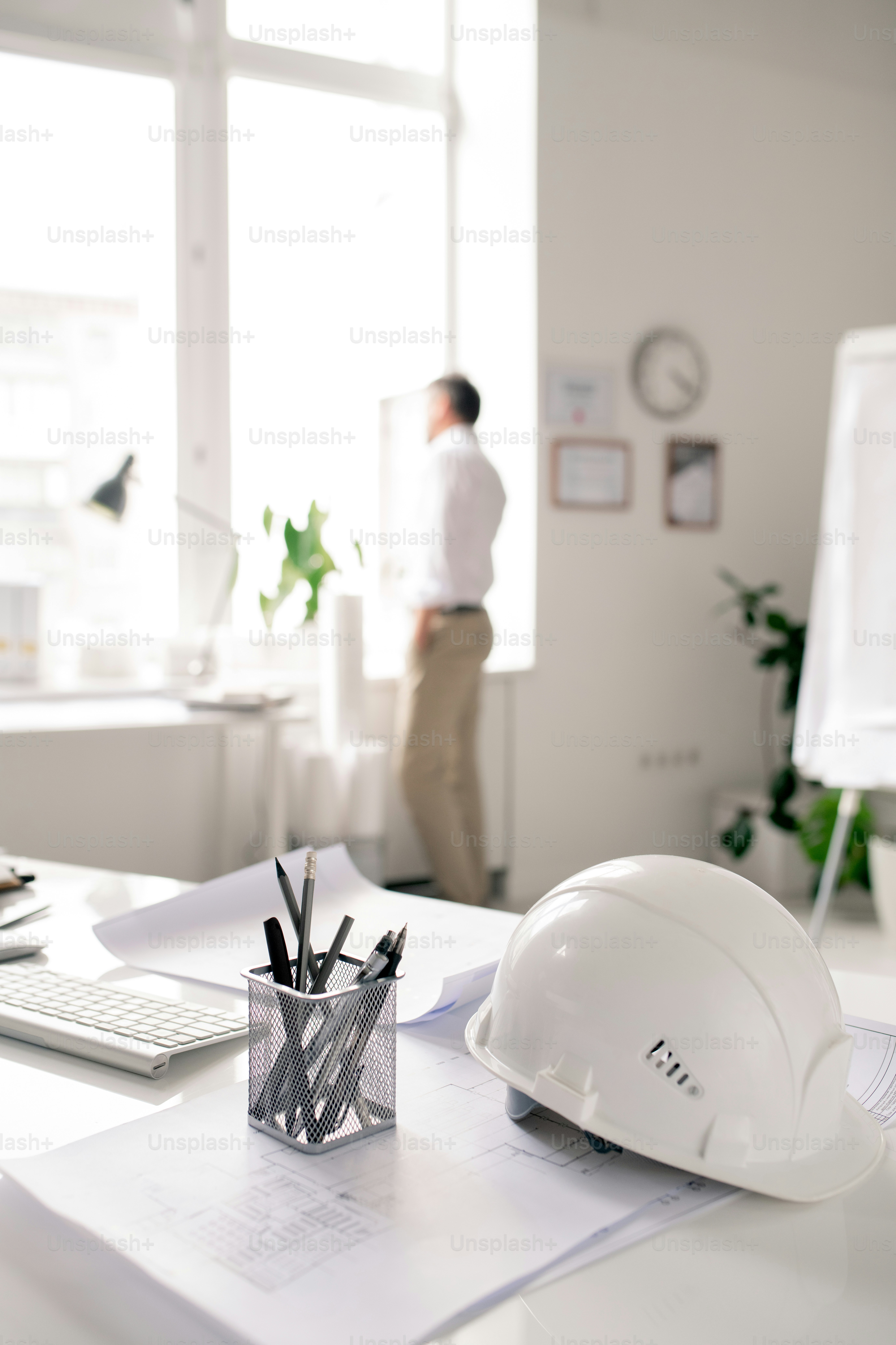 Workplace of modern architect with white hardhat, bunch of pencils and papers with sketches in office