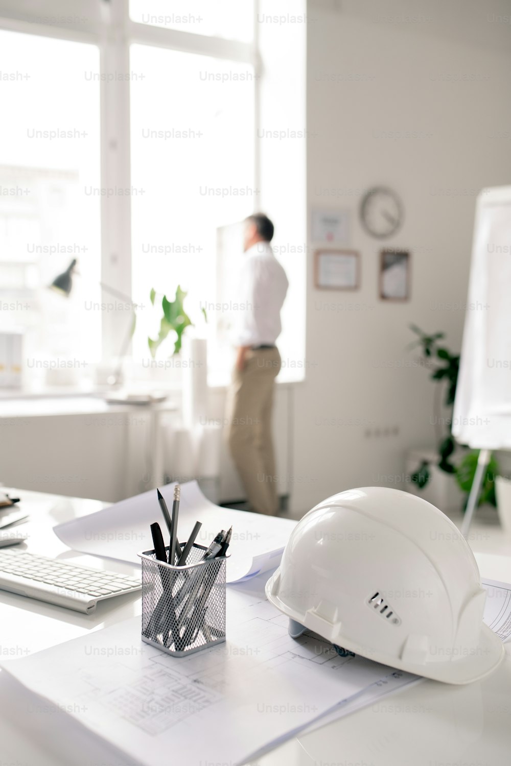 Local de trabalho de arquiteto moderno com capacete branco, monte de lápis e papéis com esboços no escritório