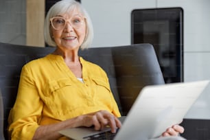 Smiling mature lady working on gadget stock photo