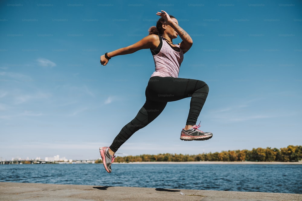 Sporty young woman making the jump by the river stock photo