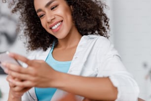 Charming young woman using smartphone and smiling stock photo