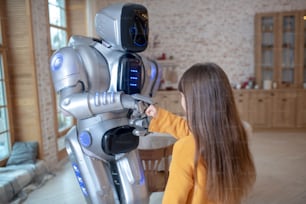 Buenos amigos. Chica con camisa naranja y robot pasando tiempo juntos