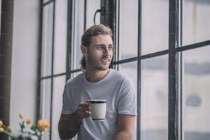 朝の飲み物。朝のコーヒーを飲むインスピレーションとエネルギッシュな長髪の男。