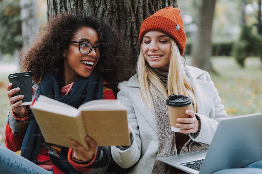 Cheerful women reading book together stock photo