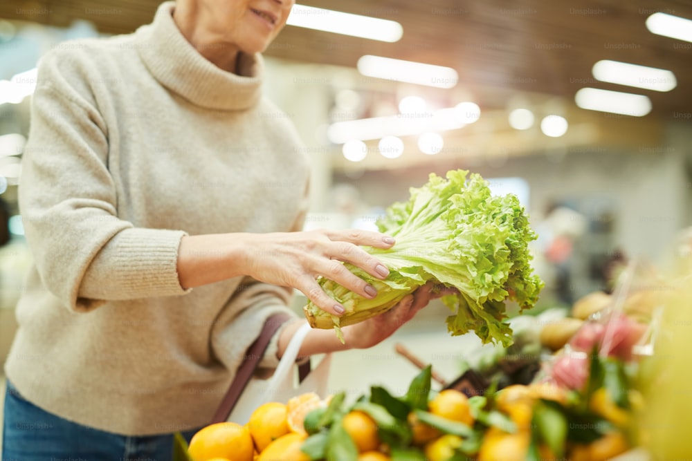 농산물 직거래 장터에서 식료품 쇼핑을 하는 동안 신선한 채소를 고르는 현대 노인 여성의 클로즈업, 복사 공간