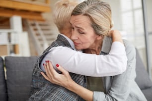 Retrato de vista lateral de psicóloga carinhosa abraçando mulher madura enquanto a conforta durante a sessão de terapia, espaço de cópia