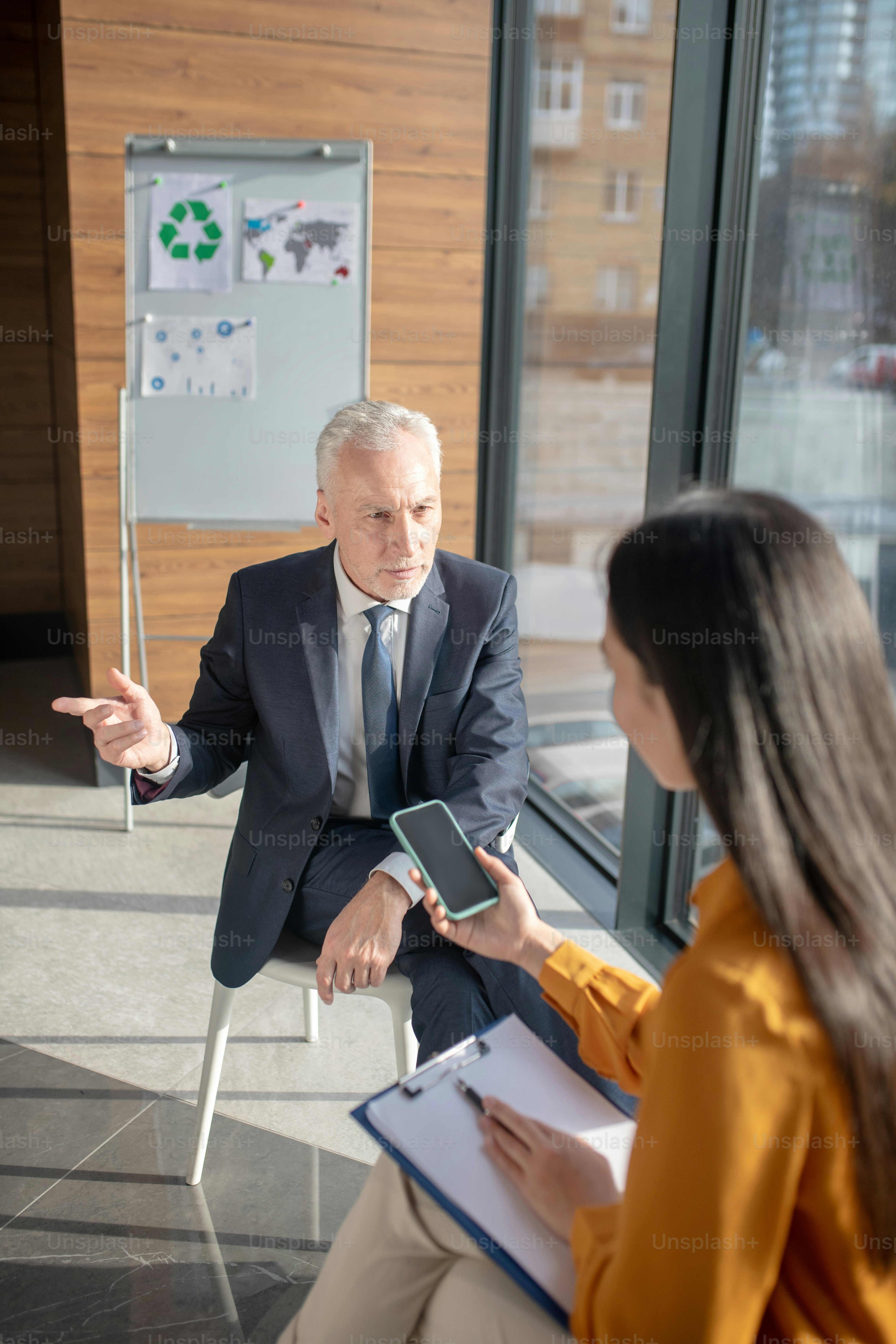Business talk. Asian female reporter with long hair having a talk with a mature businessman