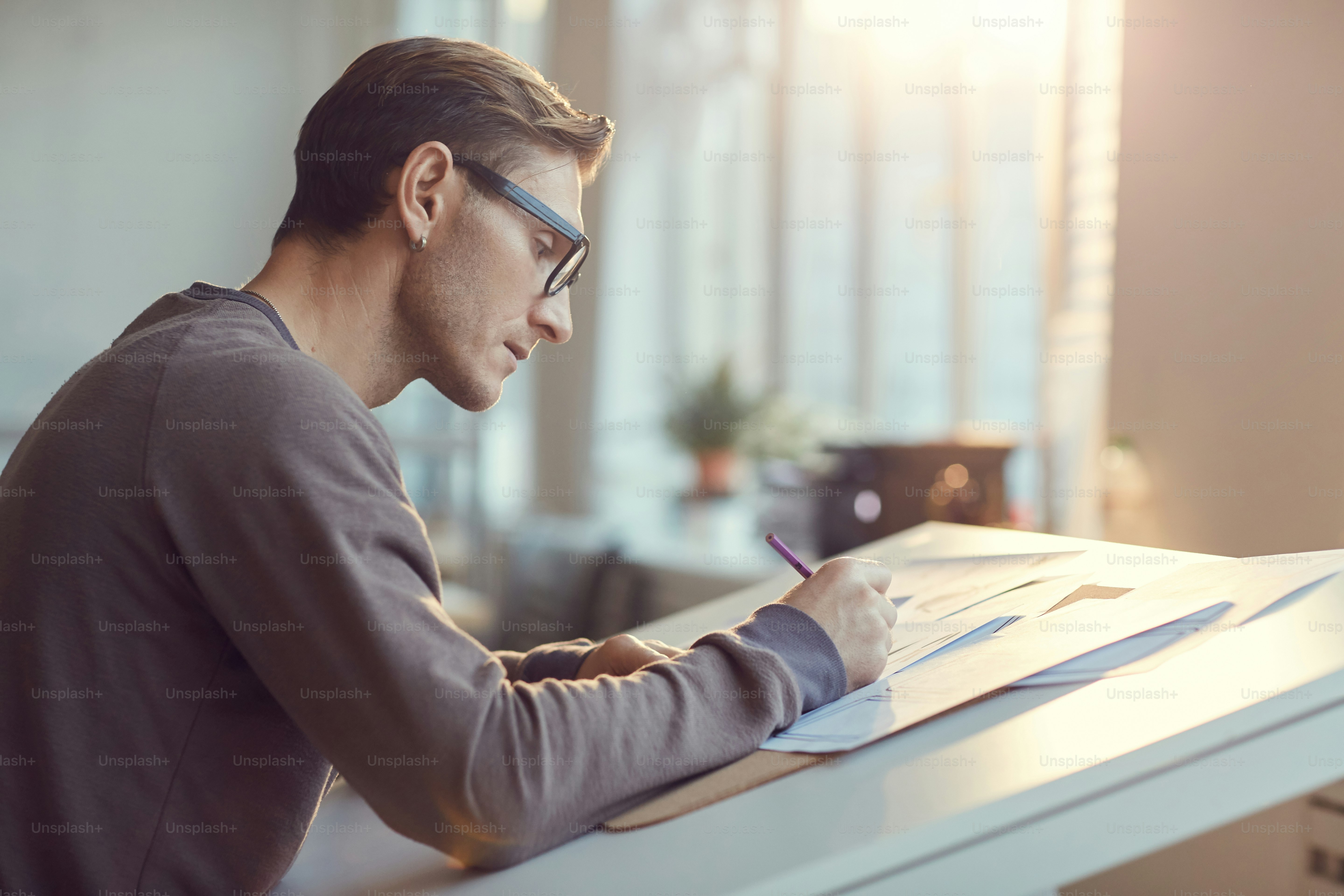 Vista laterale ritratto dell'artista contemporaneo dell'architetto che lavora al progetto di design in studio illuminato dalla luce del sole, spazio copia