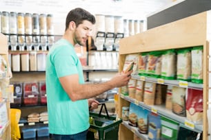Vista lateral do homem latino bonito comprando produto alimentício no supermercado