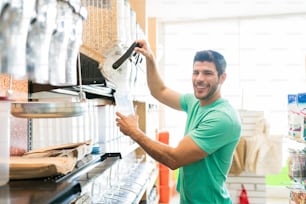 Portrait of smiling man serving food in container while buying in bulk at supermarket