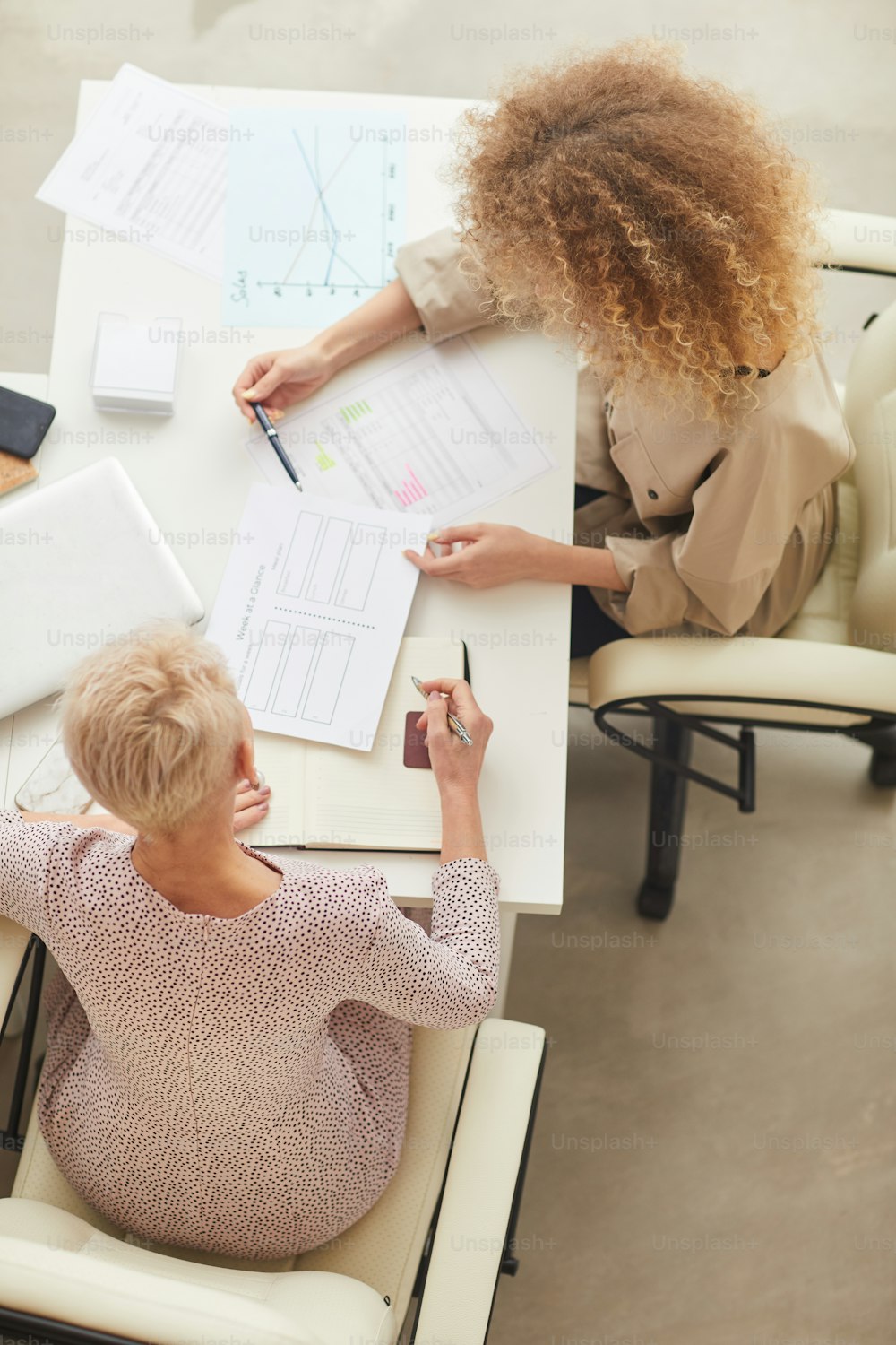 Two unrecognizable businesswomen having disscusion on new project issue vertical from above shot