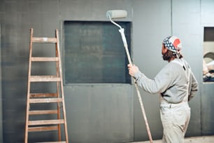 屋内でエクステンダーローラーで壁を描く画家。