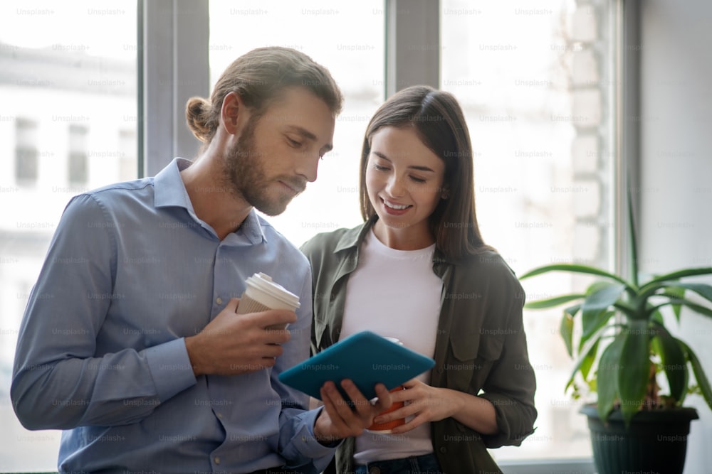 Watching pictures together. A man and a woman wahcing pictures on a tablet while having coffee