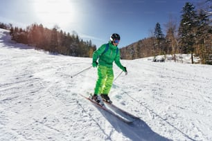 젊은 운동선수 프리스타일 스키어는 겨울철 화창한 날에 아름다운 풍경 속에서 내리막길을 달리며 즐거운 시간을 보내고 있다