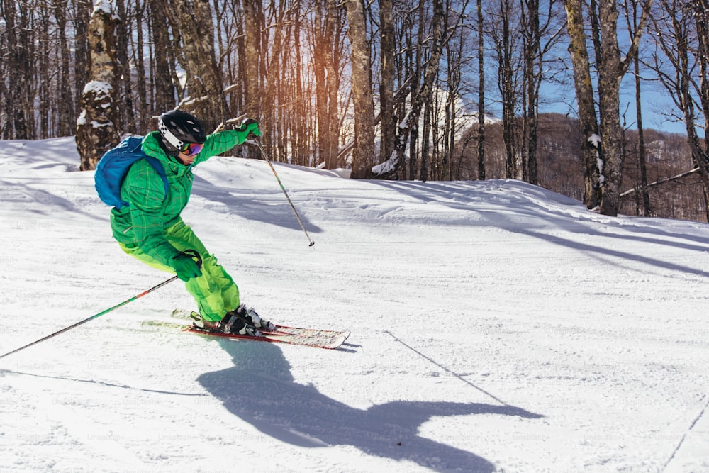 Young athlete freestyle Skier having fun while running downhill in beautiful landscape on sunny day during winter season