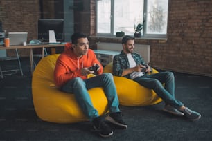 Playing video games. Joyful young men having fun while relaxing together at home