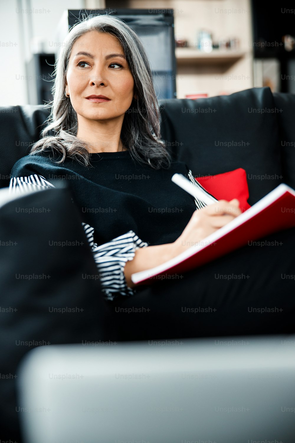 Thoughtful boss sitting in the office lobby with paperwork and looking away