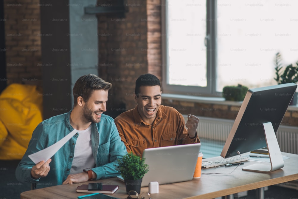 Team work. Happy cheerful men sitting together while working on a project in team