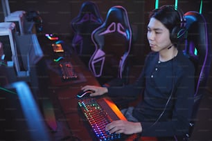 Portrait en plein angle d’un jeune homme asiatique jouant à des jeux vidéo dans une chaise de cybersport, espace de copie