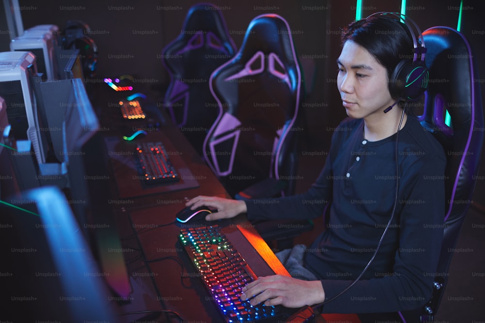 Ritratto ad angolo alto del giovane asiatico che gioca ai videogiochi in sedia sportiva cyber, spazio di copia