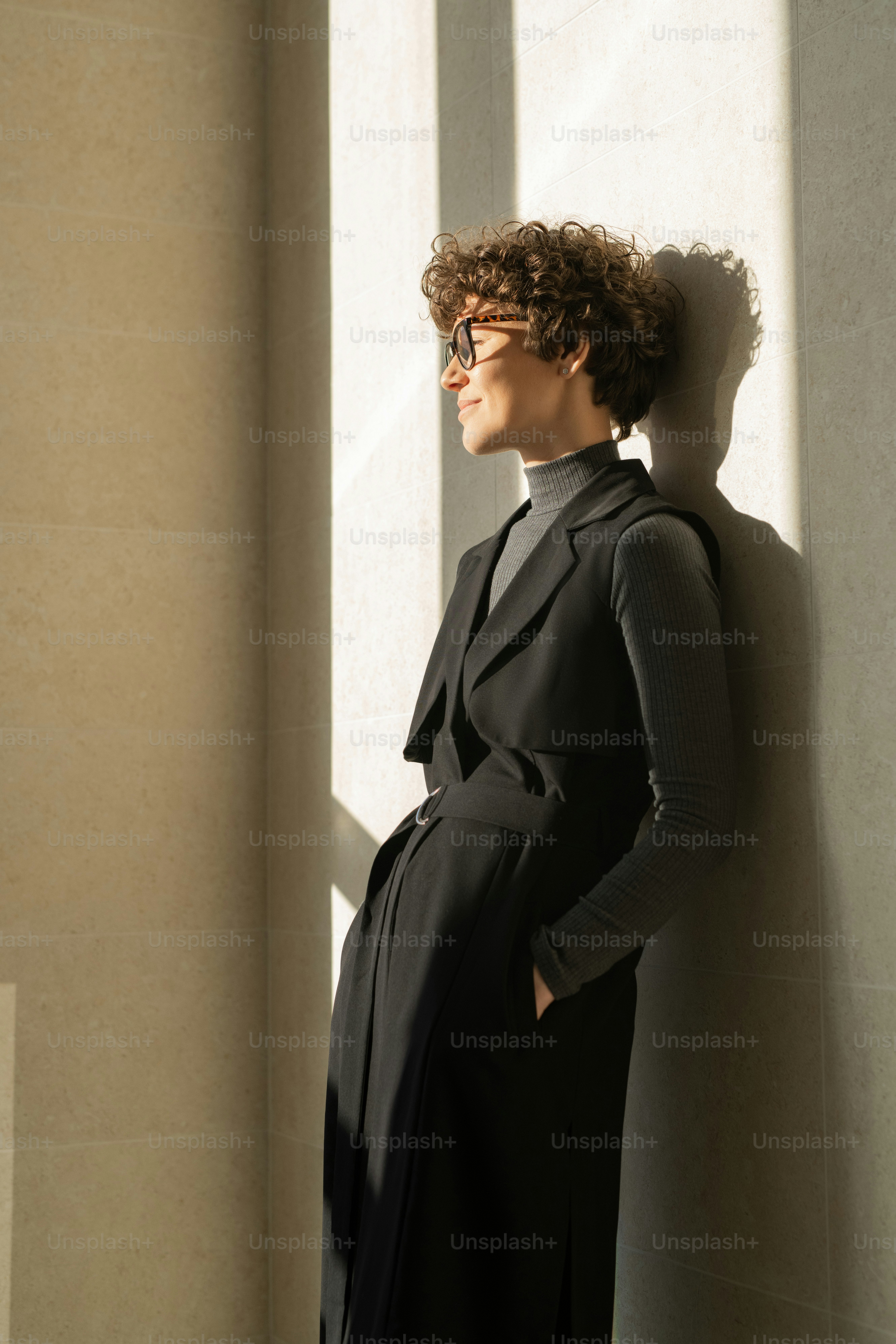 Inhalt attraktive junge Geschäftsfrau im schwarzen Kleid, die im Sonnenlicht an der Wand steht