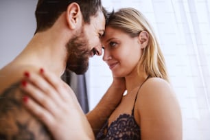 Young passionate attractive couple cuddling in bedroom.