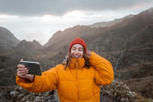 Portrait of a young traveler dressed in bright jacket and hat enjoying a trip highly in the mountains, traveling on Tenerife island, Spain