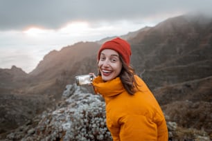 Retrato de un joven viajero vestido con chaqueta brillante y sombrero disfrutando de un viaje en lo alto de las montañas, viajando por la isla de Tenerife, España