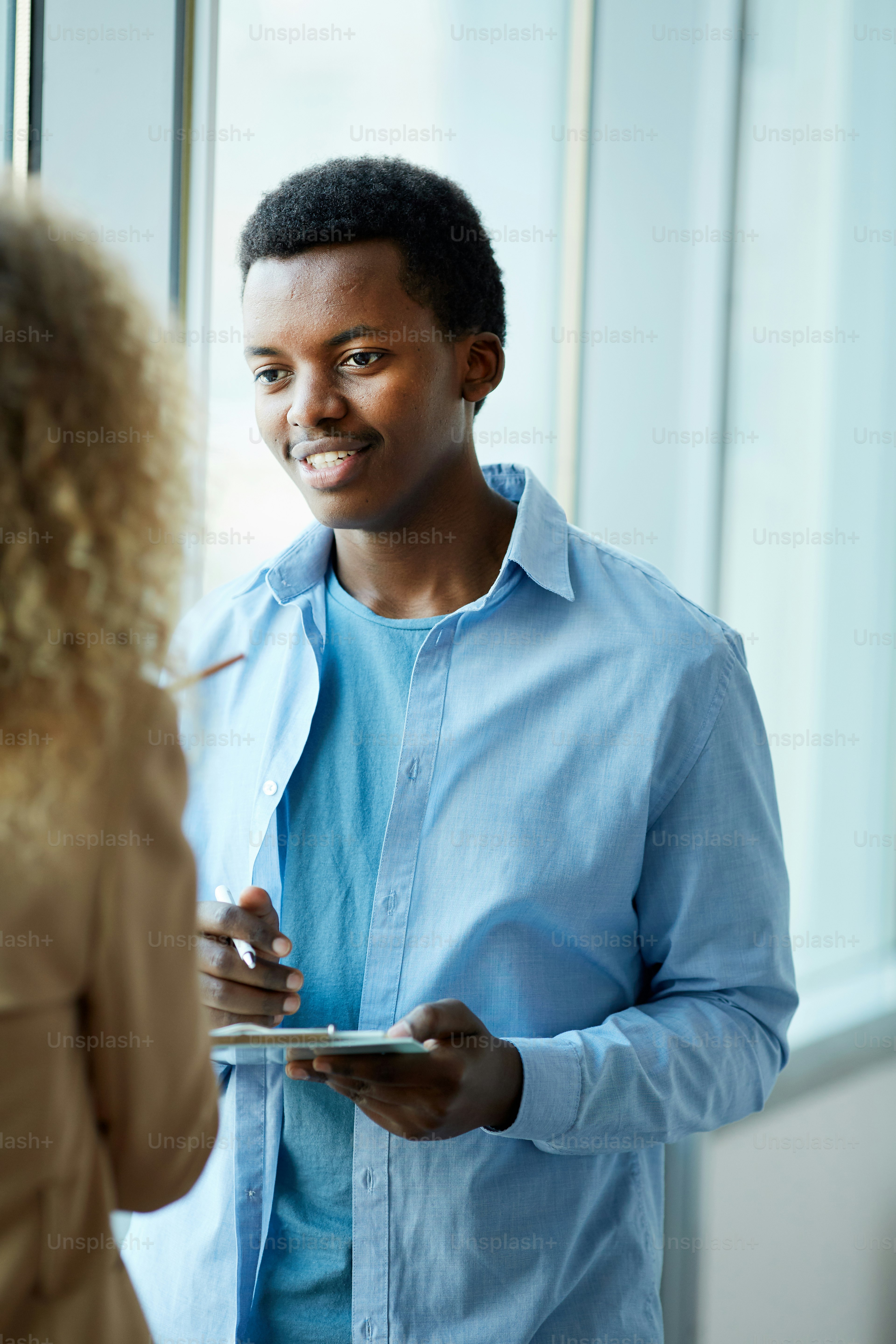Portrait vertical d'un jeune homme afro-américain parlant à une amie tout  en se tenant près d'une fenêtre dans un collège ou un bureau photo – Image  de Bureau sur Unsplash, image size:3000x4500