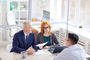 High angle view at two managers interviewing young man for job position in office, copy space