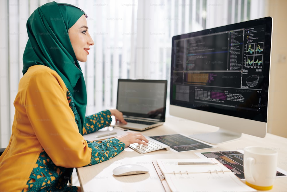 Female software developer implementing programming code she is working on laptop