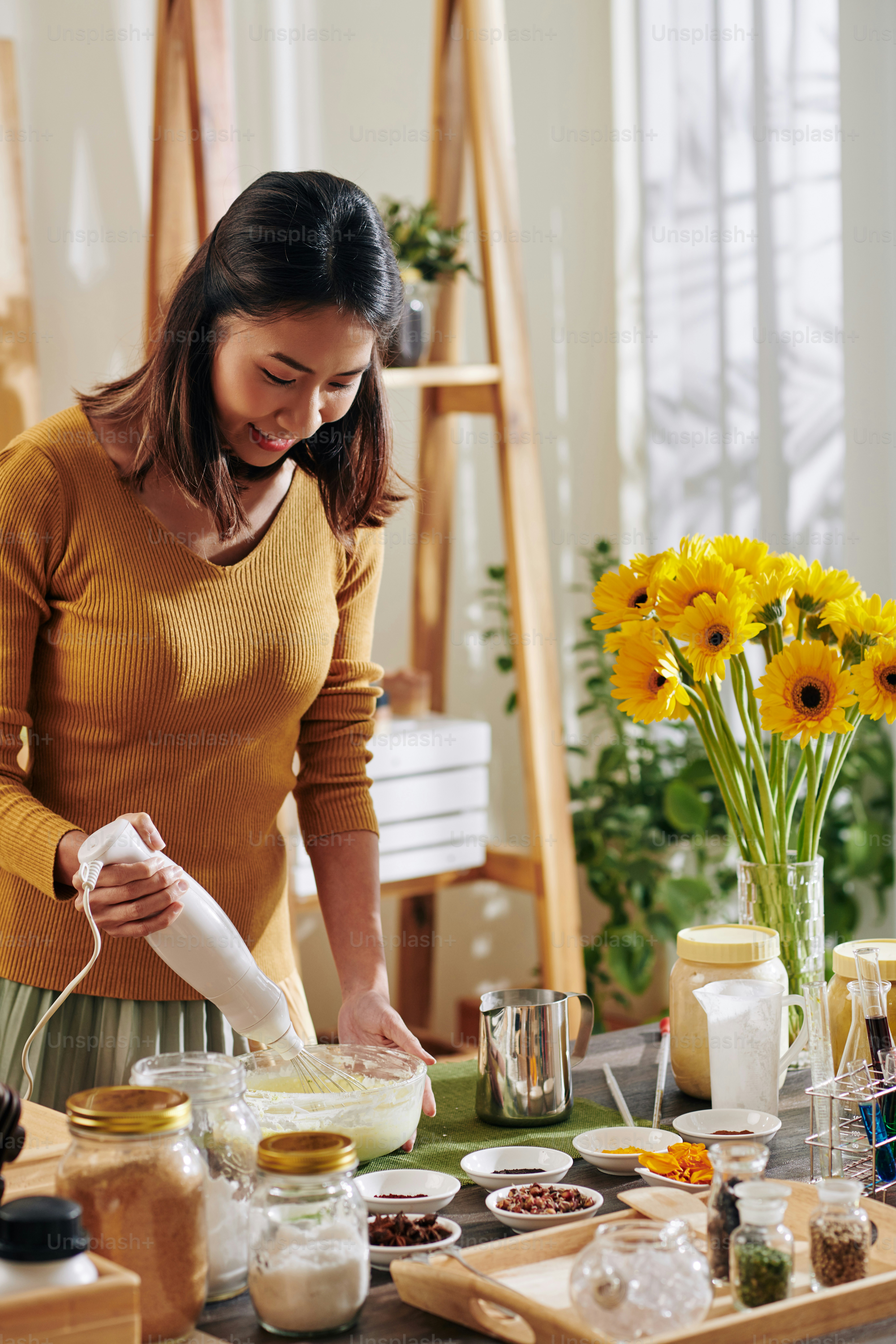 Giovane donna vietnamita positiva che usa lo sbattitore elettrico quando fa le saponette a casa