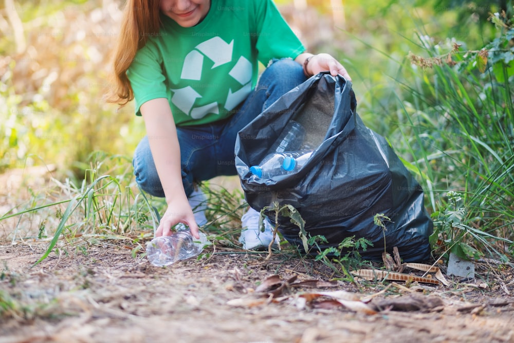 Nahaufnahme einer Frau, die Müll-Plastikflaschen in eine Plastiktüte für das Recycling-Konzept aufnimmt