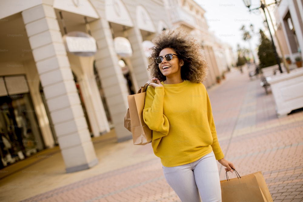 Hübsche junge schwarze Frau mit lockigem Haar beim Einkaufen