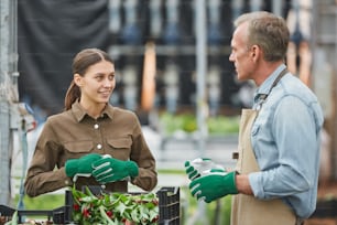 Retrato de cintura para arriba de dos trabajadores hombre y mujer joven en una plantación de flores en invernadero, espacio de copia
