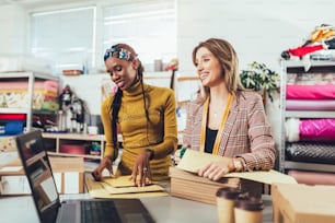 Sales Online. Working women at their store. They accepting new orders online and packing merchandise for customer.