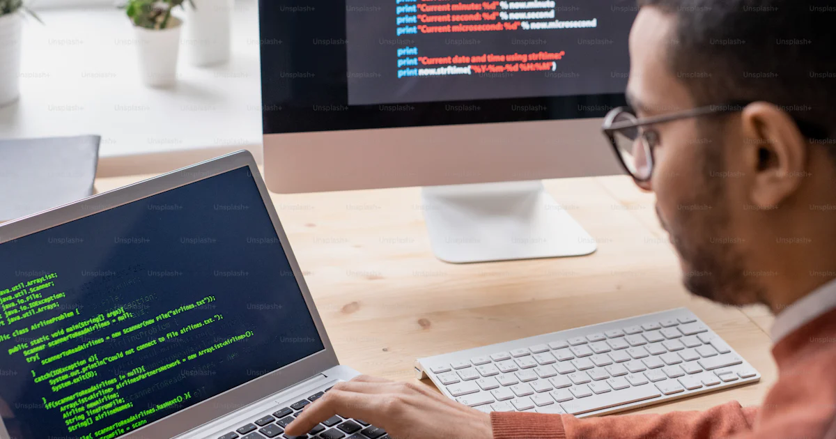 Over shoulder view of young web developer sitting at desk and working ...