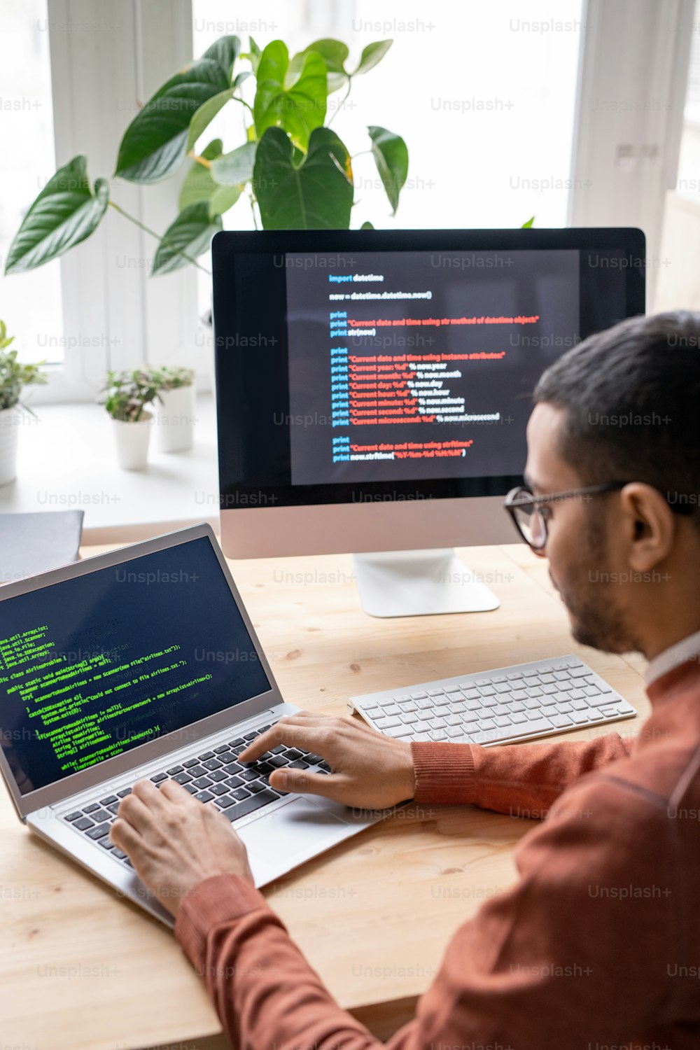 Vista sobre el hombro de un joven desarrollador web sentado en el escritorio y trabajando con una computadora portátil mientras crea un algoritmo informático