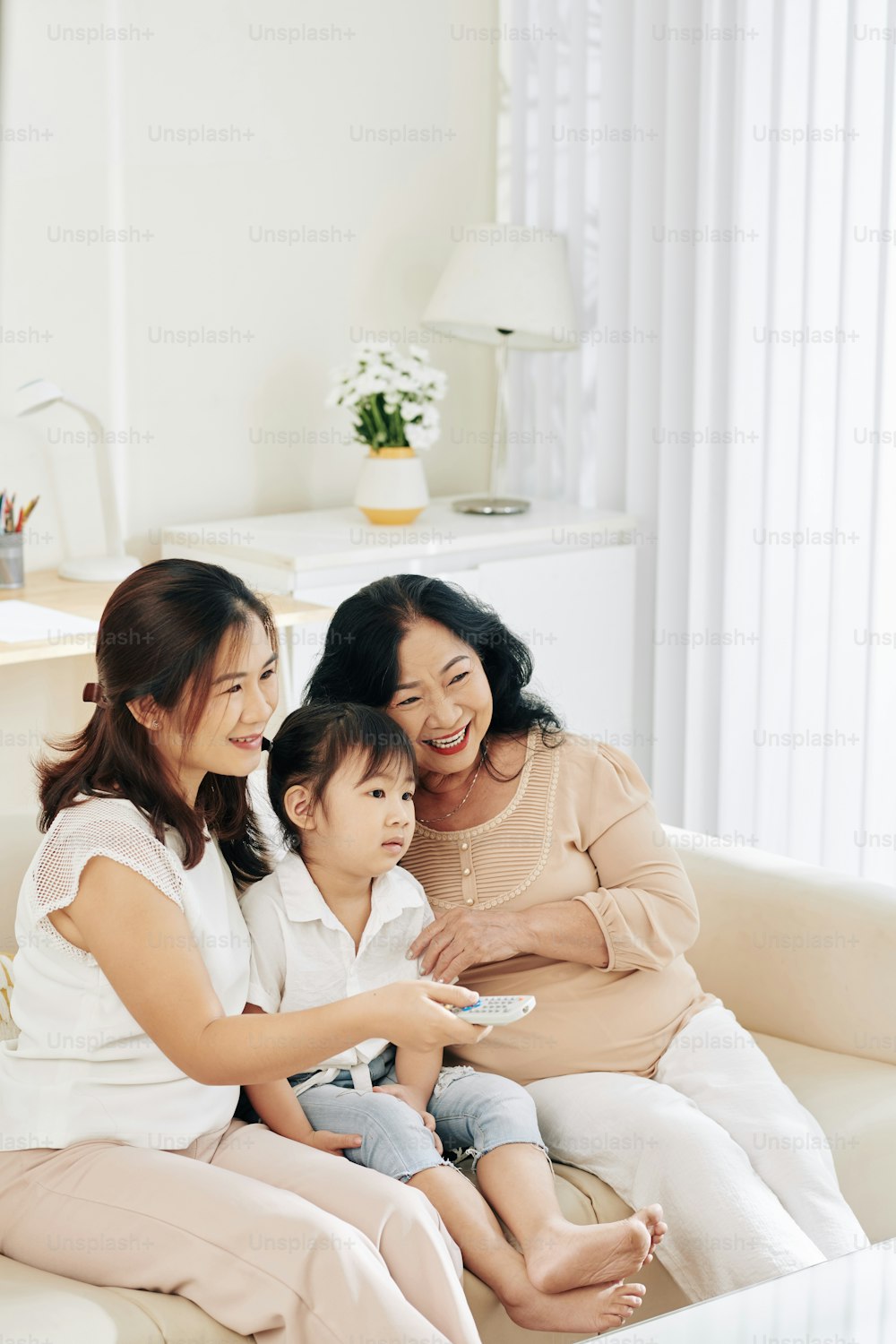 Mother, daughter and granddaughter spending time together and watching tv at home