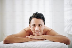 Mixed-race happy young man enjoying spending time in spa salon